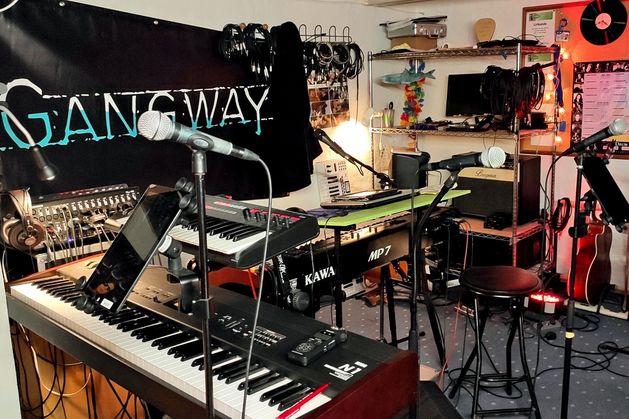Das Bild zeigt den Bandbereich im Keller der Wohnform Grauhöft. Man sieht im Vordergrund einige Tasteninstrumente und weiter hinten Teile eines Schlagzeuges und ein paar Gitarren.