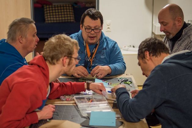 Fünf Menschen spielen und basteln zusammen am Tisch.