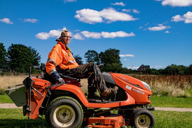 Auf dem Rasenmäher-Traktor unter blauem Himmel unterwegs.