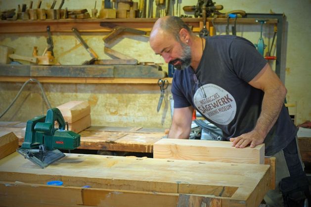 An der Tischkreissäge wird Holz gesägt.