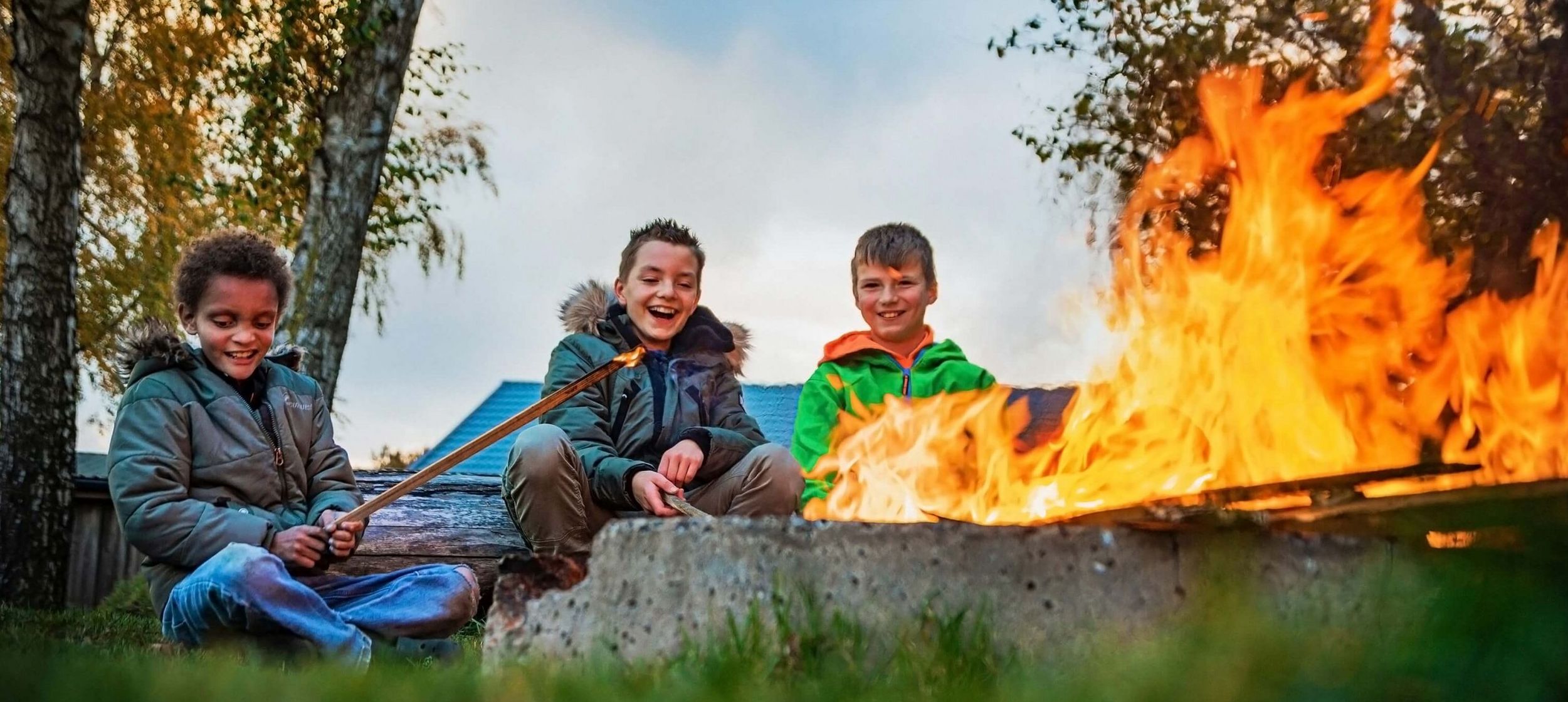 Kinder am Lagerfeuer beim Stockbrot grillen