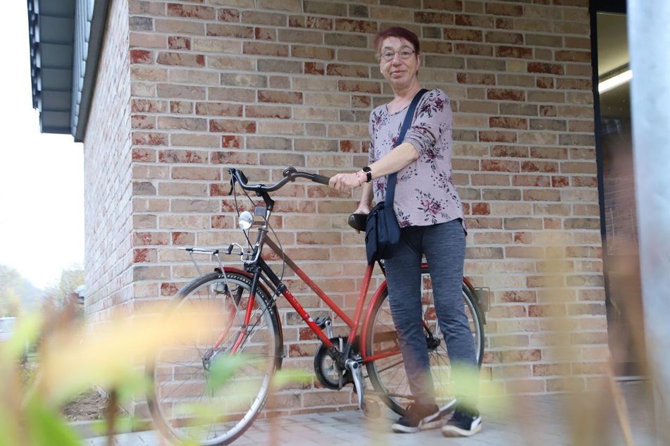 Eine Person mit Fahrrad vor dem Haus.