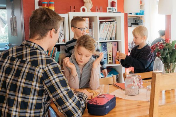 eine Person sitzt mit vielen Kindern an einem Tisch