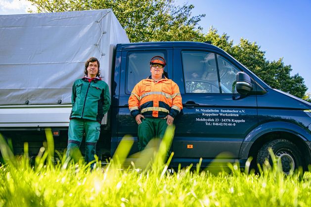 Zwei leute aus dem Gartenbereich lehnen sich an einen Transporter