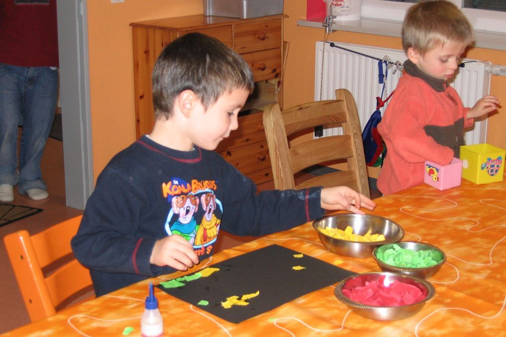 Kinder sitzen am Tisch und basteln.