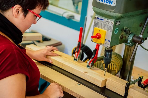 Eine Frau arbeitet an einer Maschine in der Holzwerkstatt.