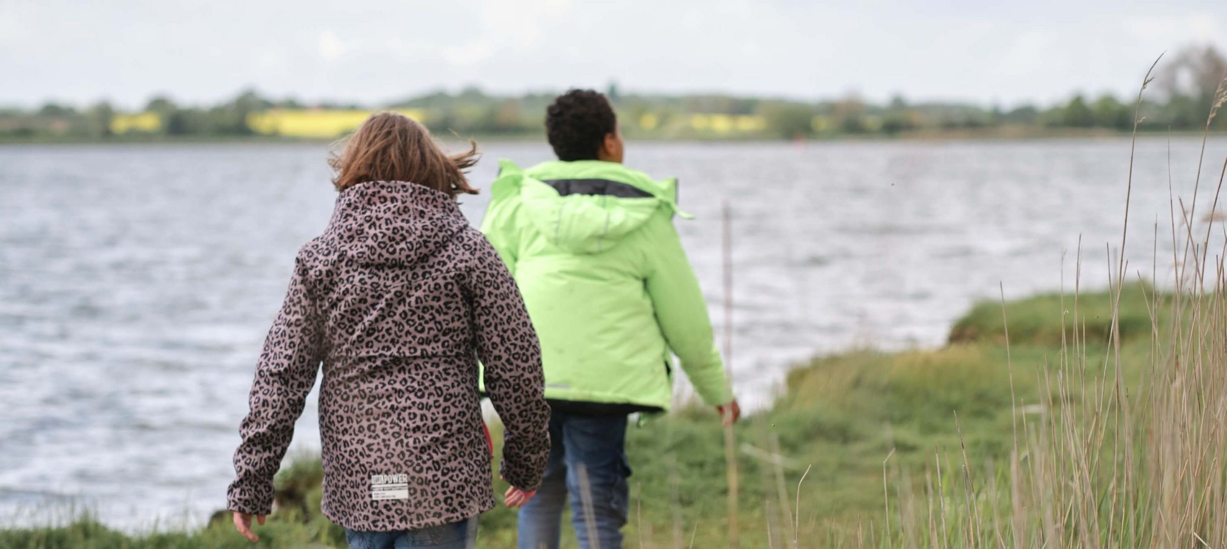 Zwei Jugendliche laufen am Ufer der Schlei