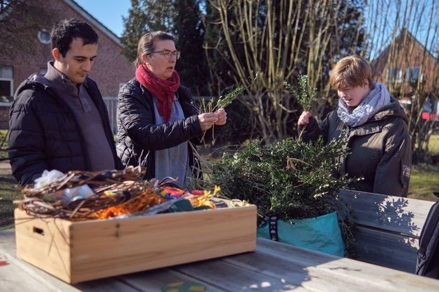 Drei Leute arbeiten gemeinsam an einem Tisch im Garten.